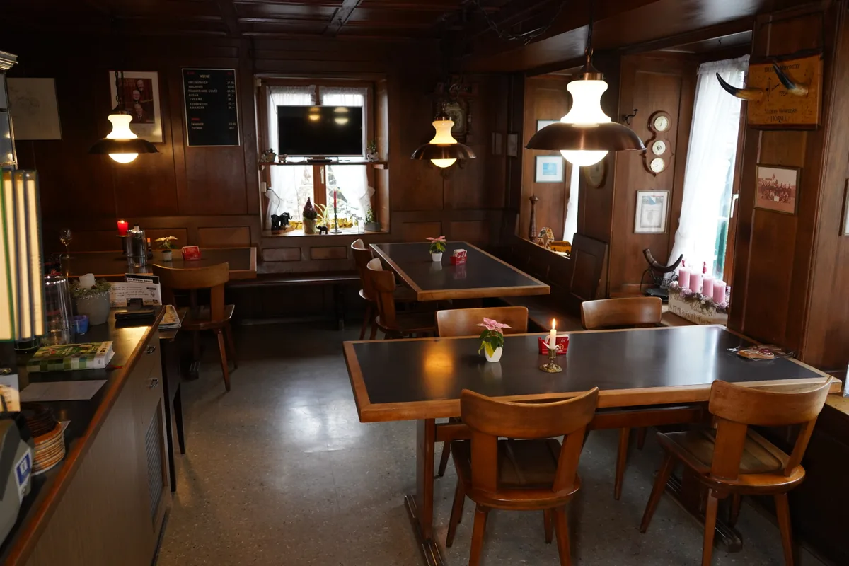 Raum mit Tischen, Stühlen und Holzwänden.